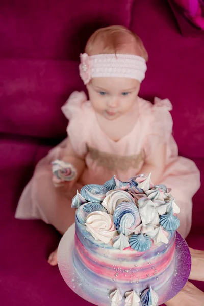Aniversariante morde um pedaço de bolo sentado no sofá cercado por balões. Foco no bolo Fotografias De Stock Royalty-Free