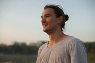 Parkta gülümseyen yakışıklı adam.