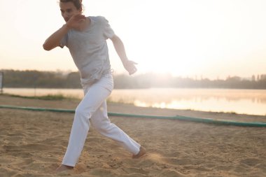 Sahilde hareketleri yapma atletik capoeira sanatçı