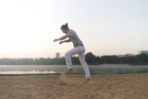 Casual atletische man Maak je klaar om te springen op het strand terwijl training — Stockfoto