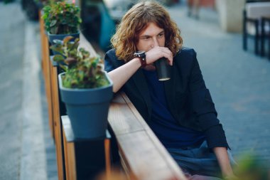 Bir kahve ile bir bankta oturan adam gitmek