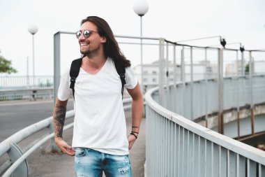 Dışarı, şehirde yürüyüş gülümseyen adam asmak