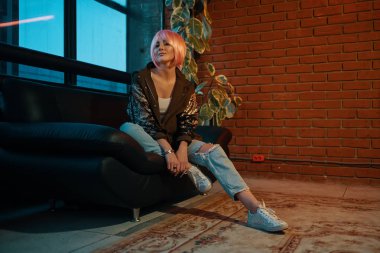 Deri kanepede oturan pembe saçlı kız rahat