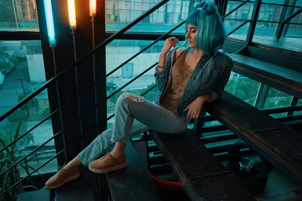 Mujer elegante con una peluca azul sentado en las escaleras en un moderno — Foto de Stock