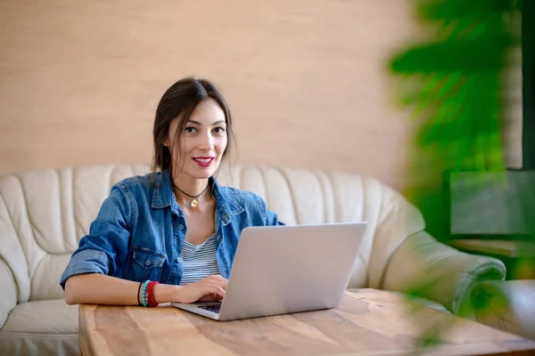 Усміхнена молода жінка друкує на ноутбуці — стокове фото