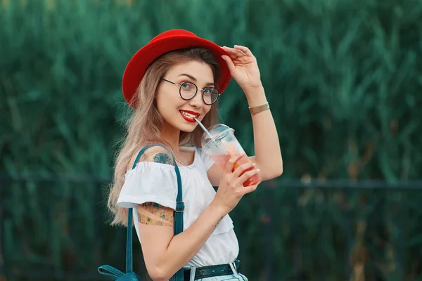 Uma jovem mulher elegante que toma uma bebida refrescante enquanto caminha — Fotografia de Stock