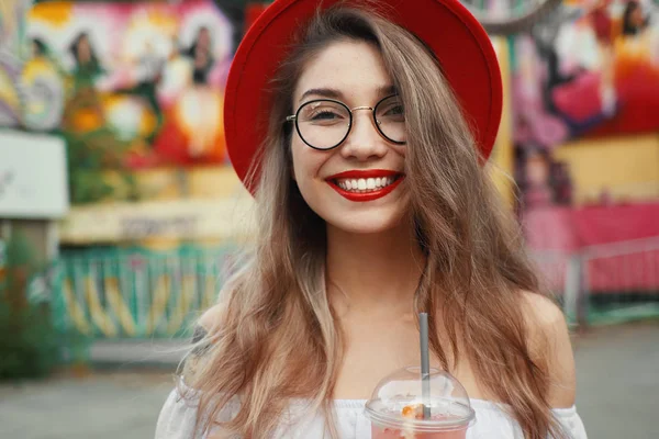 Весела молода жінка тримає напій, посміхаючись — стокове фото