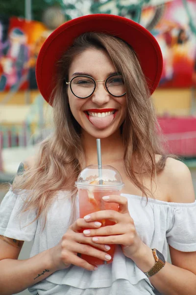 Весела молода жінка тримає напій, посміхаючись — стокове фото