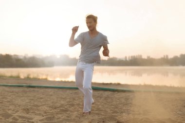 Sahilde hareketleri yapma atletik capoeira sanatçı