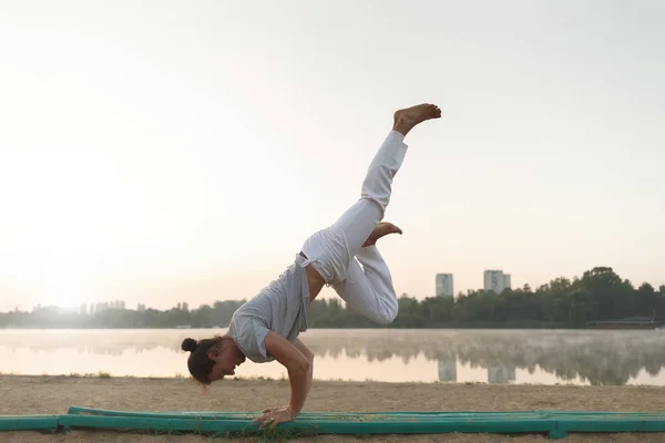 Joven atlético haciendo yoga posa cerca de la laca — Foto de Stock