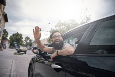 Neşeli adam bir araba sürüş sırasında sallayarak