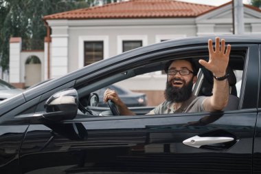 Neşeli adam bir araba sürüş sırasında sallayarak