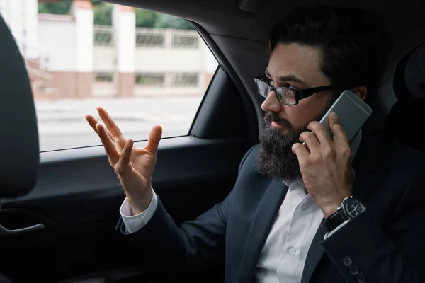 A businessman while traveling by car in the back seat using a sm — Stock Photo, Image