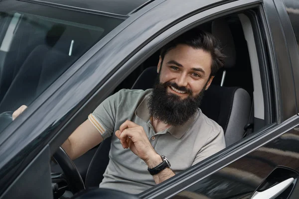 Молодой человек улыбается за рулём автомобиля — стоковое фото