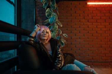 Deri kanepede oturan pembe saçlı kız rahat