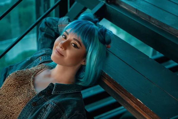 Stylische Frau mit blauer Perücke auf der Treppe liegend mit Blick auf c — Stockfoto