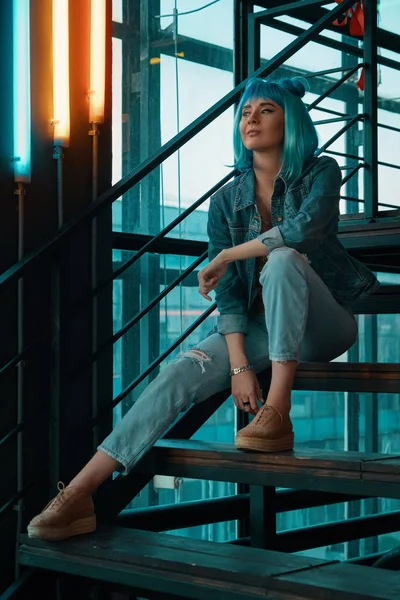 Mujer elegante con una peluca azul sentado en las escaleras en un moderno — Foto de Stock