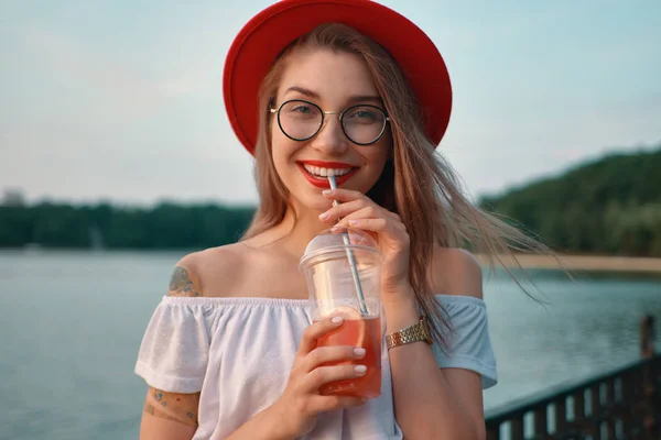 Una mujer joven y elegante tomando una bebida refrescante mientras busca —  Fotos de Stock