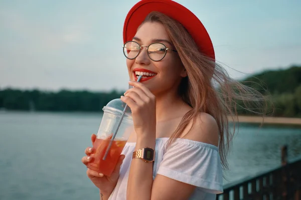 A Young stylish woman having a refreshing drink while smiling — Stock Photo, Image
