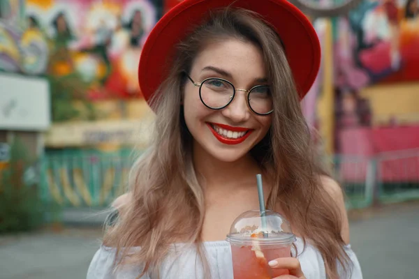 Veselá mladá žena držící drink při úsměvu — Stock fotografie