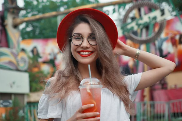 Veselá mladá žena držící drink při úsměvu — Stock fotografie