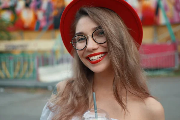 Veselá mladá žena držící drink při úsměvu — Stock fotografie
