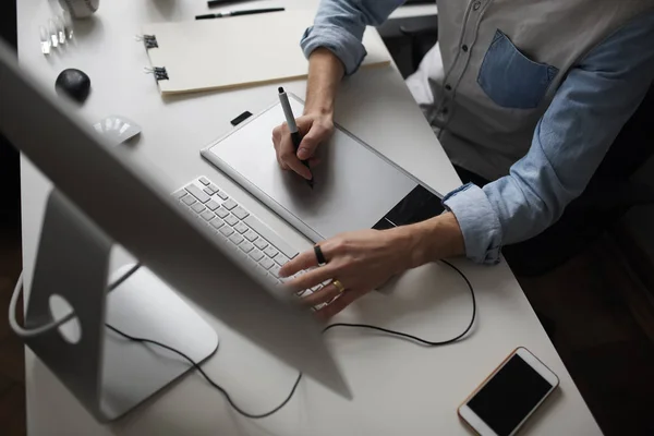 Joven diseñador masculino utilizando gráficos tableta mientras trabaja con com — Foto de Stock