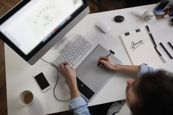 Jonge mannelijke ontwerper gebruiken grafisch tablet terwijl u werkt met com — Stockfoto