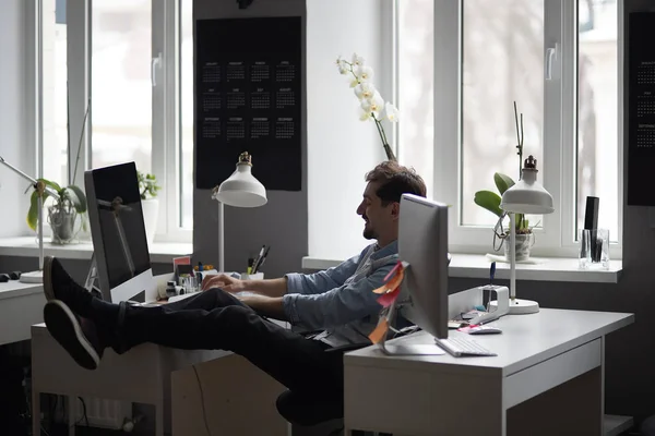 Jonge intelligente bebaarde man werken en lachend in moderne loft — Stockfoto