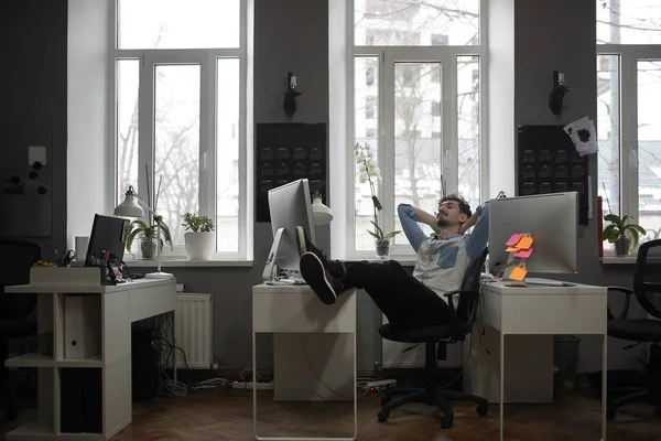 En man som funderar på en semester i ett modernt kontor medan du kopplar av — Stockfoto
