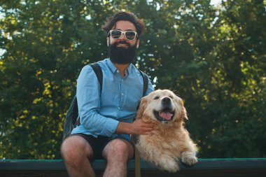 İlginç adam köpeğiyle en park sandalyede oturuyor
