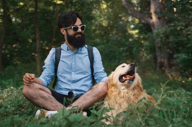 Oturan çimenlerin üzerinde oturan adam köpeğiyle bacak bacak