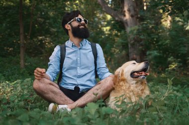 Oturan çimenlerin üzerinde oturan adam köpeğiyle bacak bacak