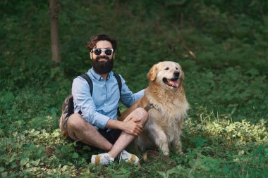 Oturan çimenlerin üzerinde oturan adam köpeğiyle bacak bacak