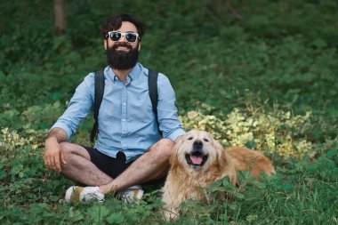 Oturan çimenlerin üzerinde oturan adam köpeğiyle bacak bacak