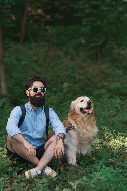 Oturan çimenlerin üzerinde oturan adam köpeğiyle bacak bacak