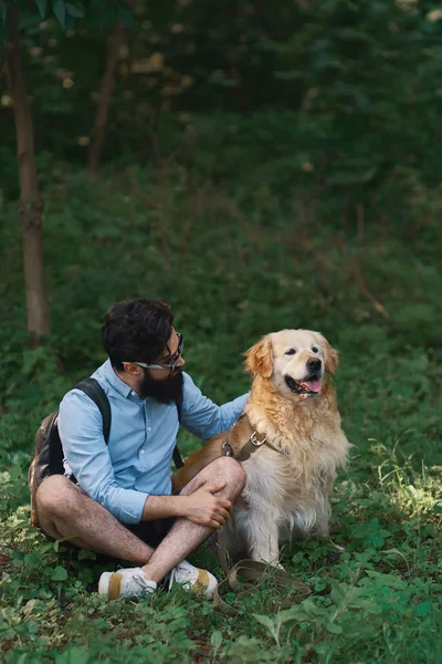 Hombre descansando sobre la hierba sentado piernas cruzadas con su perro —  Fotos de Stock
