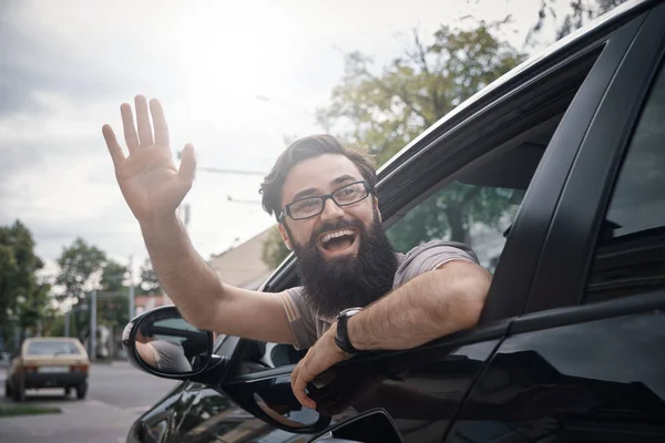 Cheerful man waving while driving a car — Stock Photo, Image