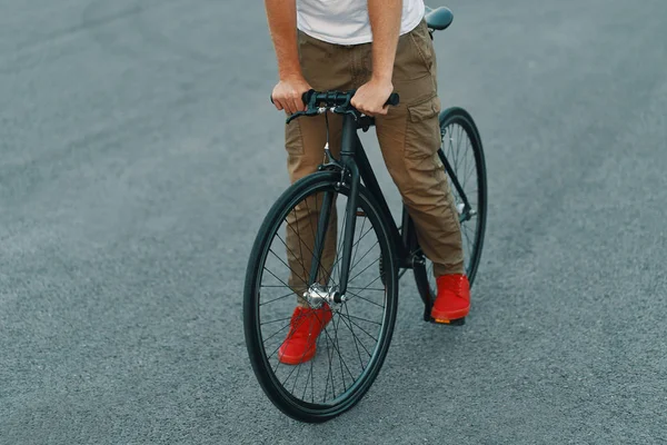 特写的休闲男子腿骑经典自行车在城市灰色的道路上穿着红色运动鞋和舒适的裤子 复制空间 — 图库照片