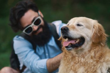 Portre, köpek, golden retriever odaklanmak kapatın. Resim kırpılmış, gülümseyen güneş gözlüğü, dost hayvanını yumuşak kürk taping adamla sakallı.