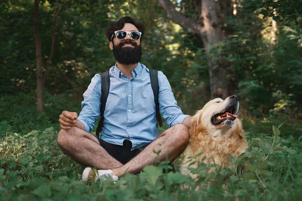 Όμορφος Άνθρωπος Αναπαύεται Στο Γρασίδι Κάθεται Σταυρωμένα Πόδια Αξιολάτρευτο Σκυλί — Φωτογραφία Αρχείου