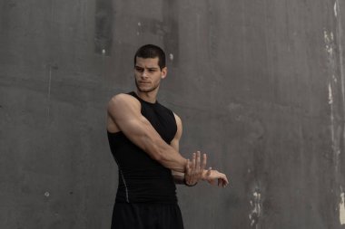 Isınma, arka planda gri bir kentsel Duvar ile eğitim için hazırlık güçlü kas, sportif adam. Genç sporcu elleri ve triceps germe. Egzersiz ve egzersiz kavramı