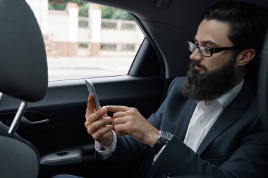 Araba ile arka koltukta seyahat ederken bir iş adamı. Yakışıklı bir genç adam arıyor ve arabada otururken akıllı telefonundan mesaj yazarak tam takım.
