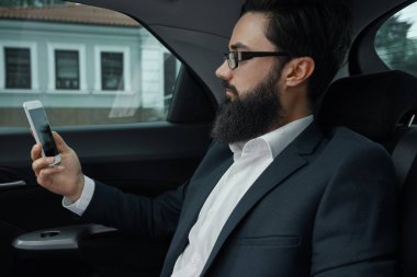 Araba ile arka koltukta seyahat ederken bir iş adamı. Tam takım seyir onun akıllı telefon arabada otururken yakışıklı bir genç adam