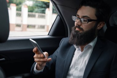 Araba ile arka koltukta seyahat ederken bir iş adamı. Yakışıklı bir genç adam arıyor ve arabada otururken akıllı telefonundan mesaj yazarak tam takım.