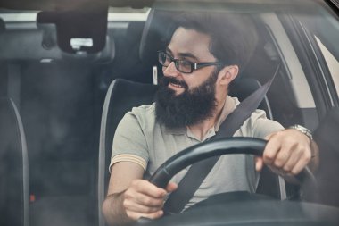 Sahne, ön cam camdan gördüm bakarak bir aracın sürüş genç çekici biri. Mutlu sürücü, geniş güzel bir gülümseme ile direksiyon simidi üzerinde ellerimi.