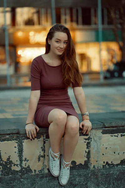 Hermosa chica solitaria sentada en la ciudad con luz en la espalda — Foto de Stock