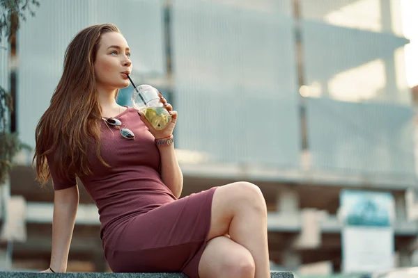 Mujer alegre en la calle bebiendo bebida refrescante por la mañana — Foto de Stock