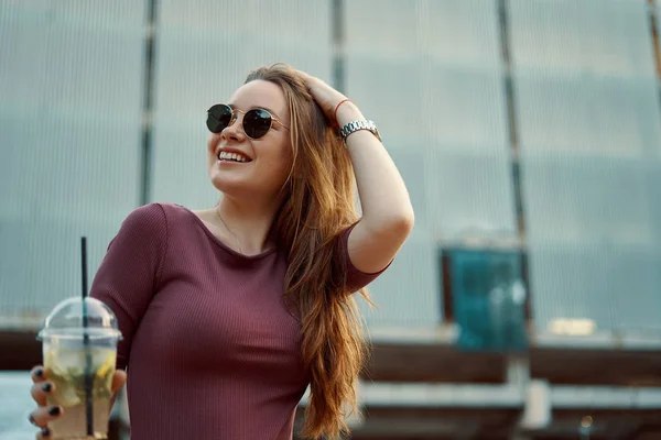 Mujer alegre en la calle bebiendo bebida refrescante por la mañana —  Fotos de Stock