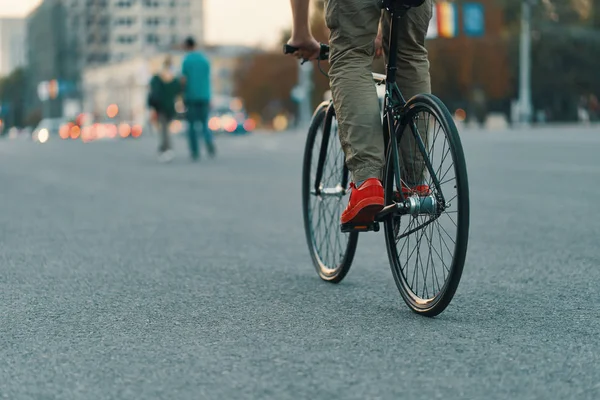 特写的休闲男子腿骑经典自行车在城市灰色的道路上穿着红色运动鞋和舒适的裤子 复制空间 — 图库照片